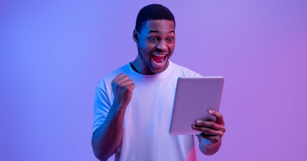 Homem negro vibrando com conteúdo visualizado em tablet - Publicidade online