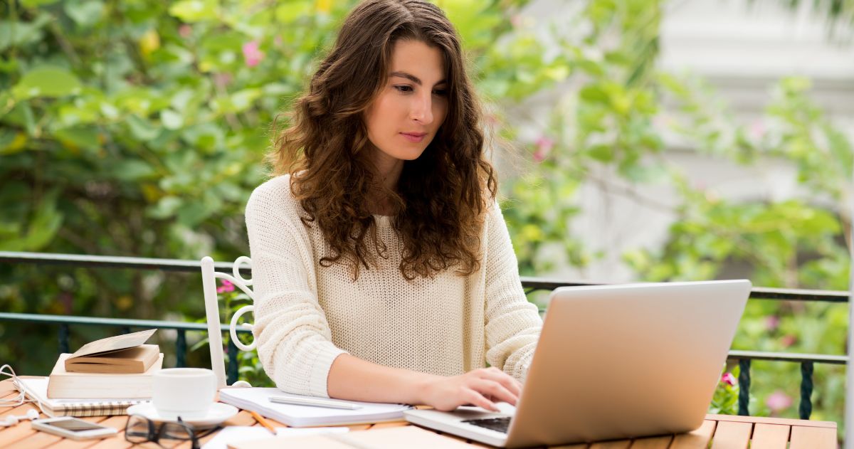 Copy para Vendas - escritora do sexo feminino em ambiente externo com seu laptop e folhas de papel
